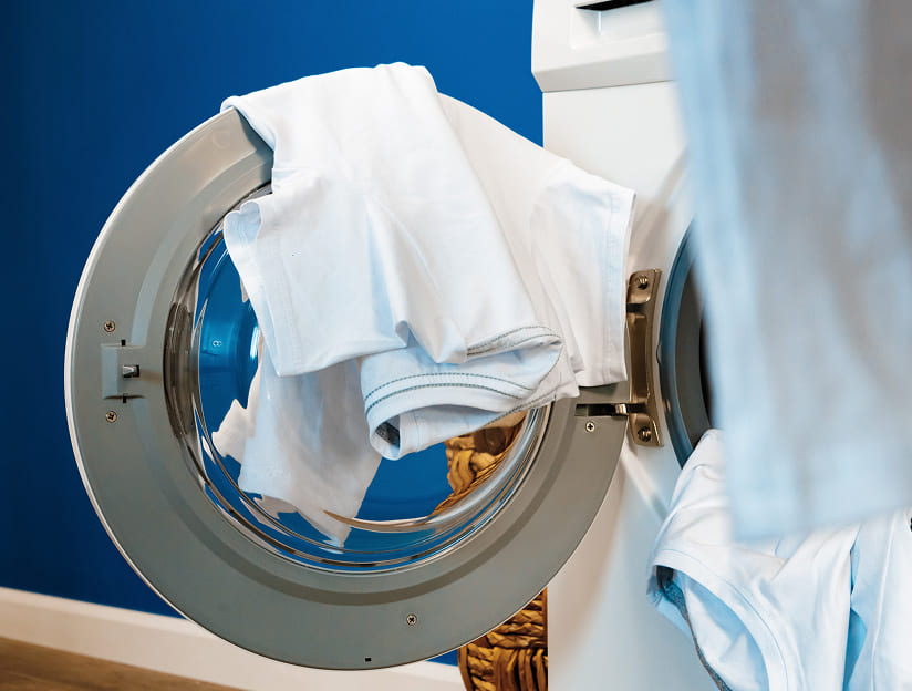 Close-up of a washing machine door with freshly laundered white garments